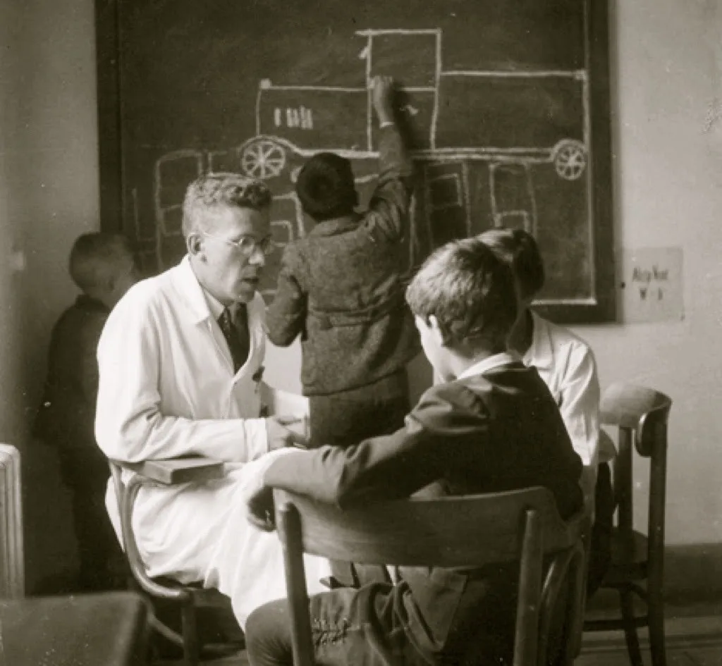 Hans Asperger cu copii la clinica din Viena — un copil deseneaza la tabla